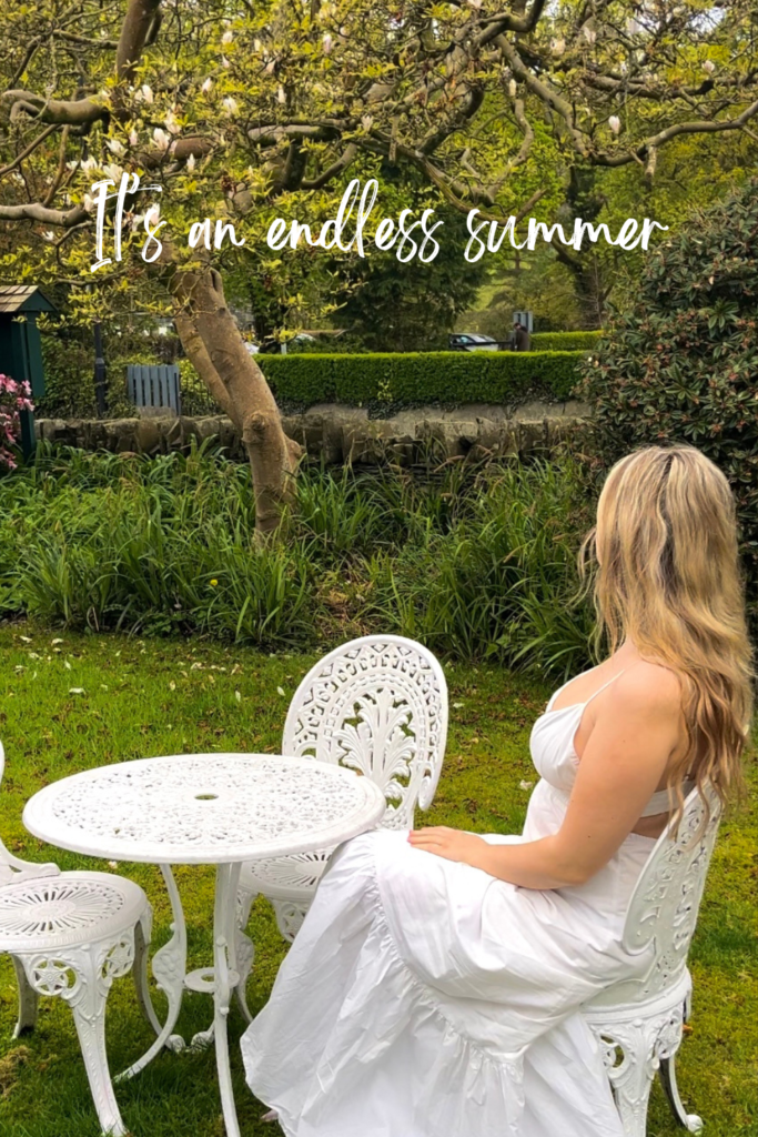 blonde woman in white dress on a white garden table in the lake district 