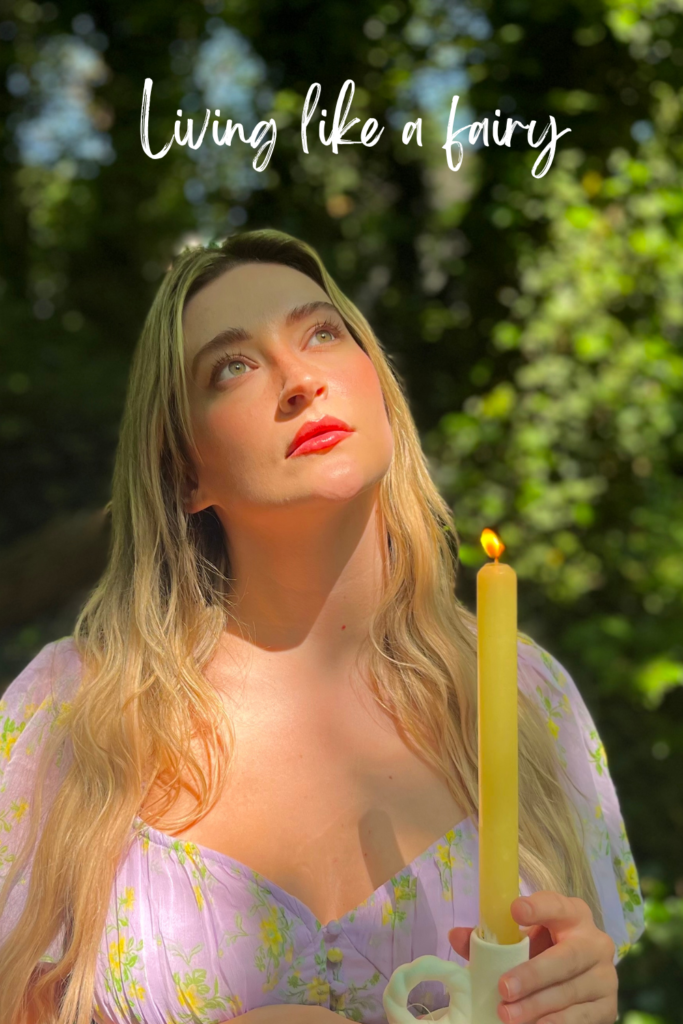 blonde woman in purple dress holding a candle in the forest at golden hour 