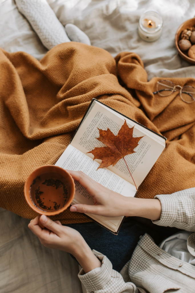 fall mug of tea with book and autumn leaf 